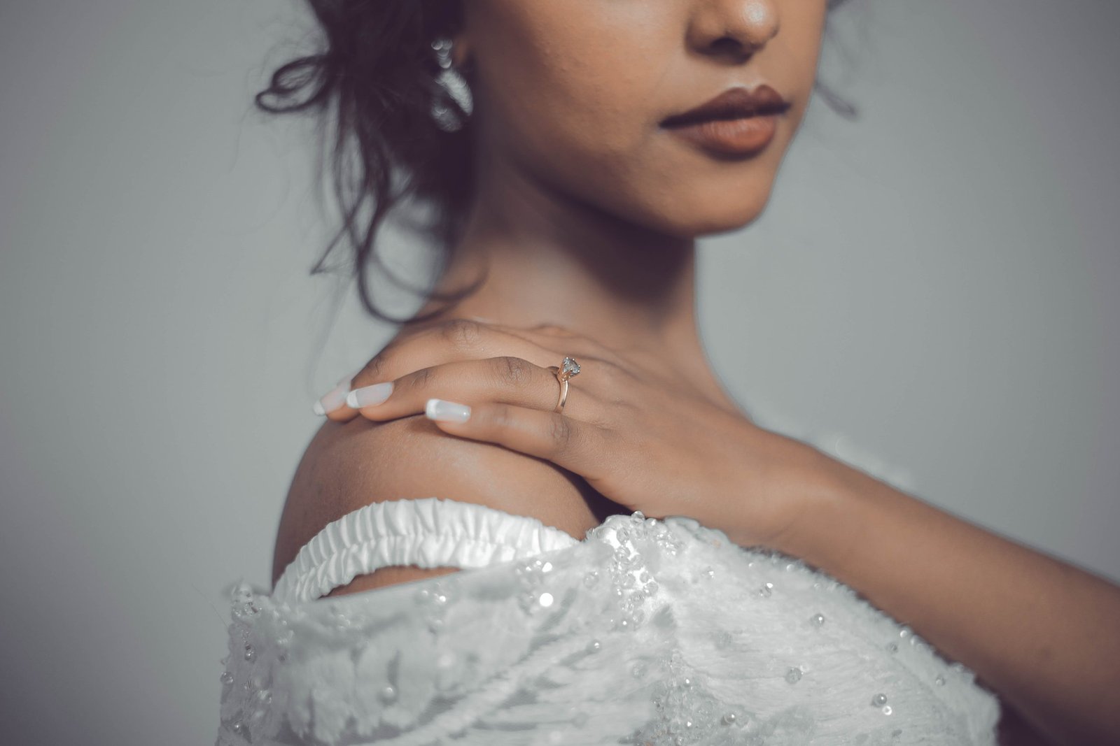 woman in white wedding dress with hand on shoulder and gold diamond ring